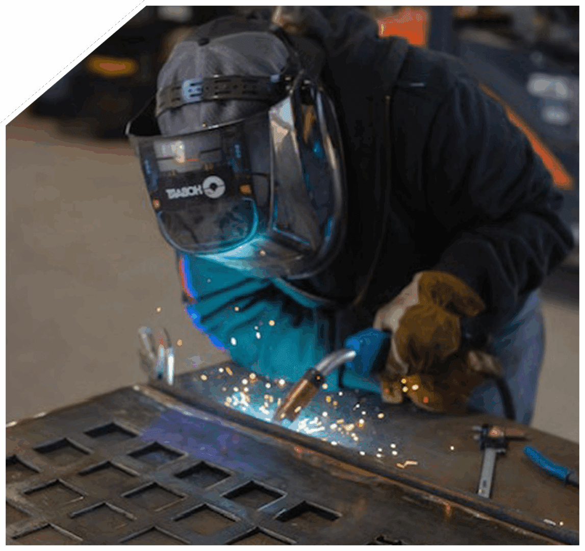 Person welding metal wearing protective gear.