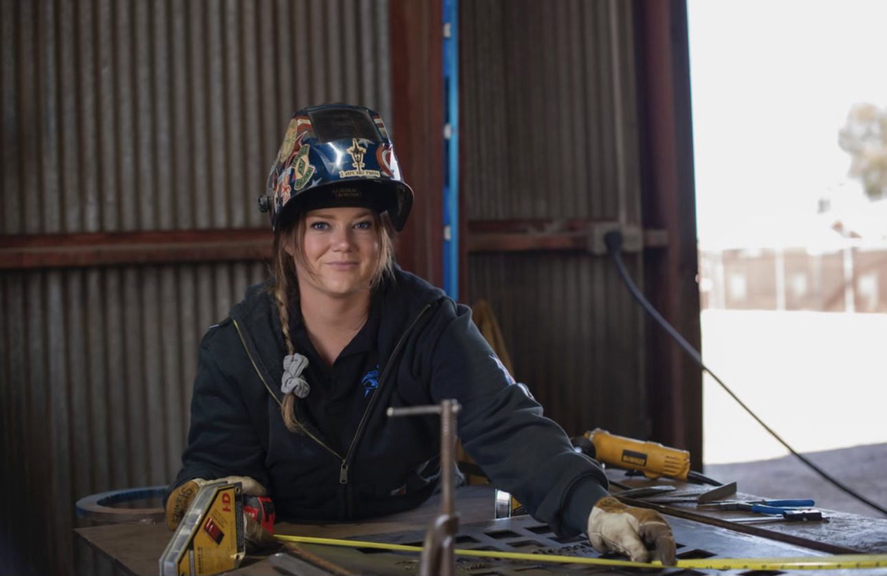 Smiling welder in protective gear at a workshop.
